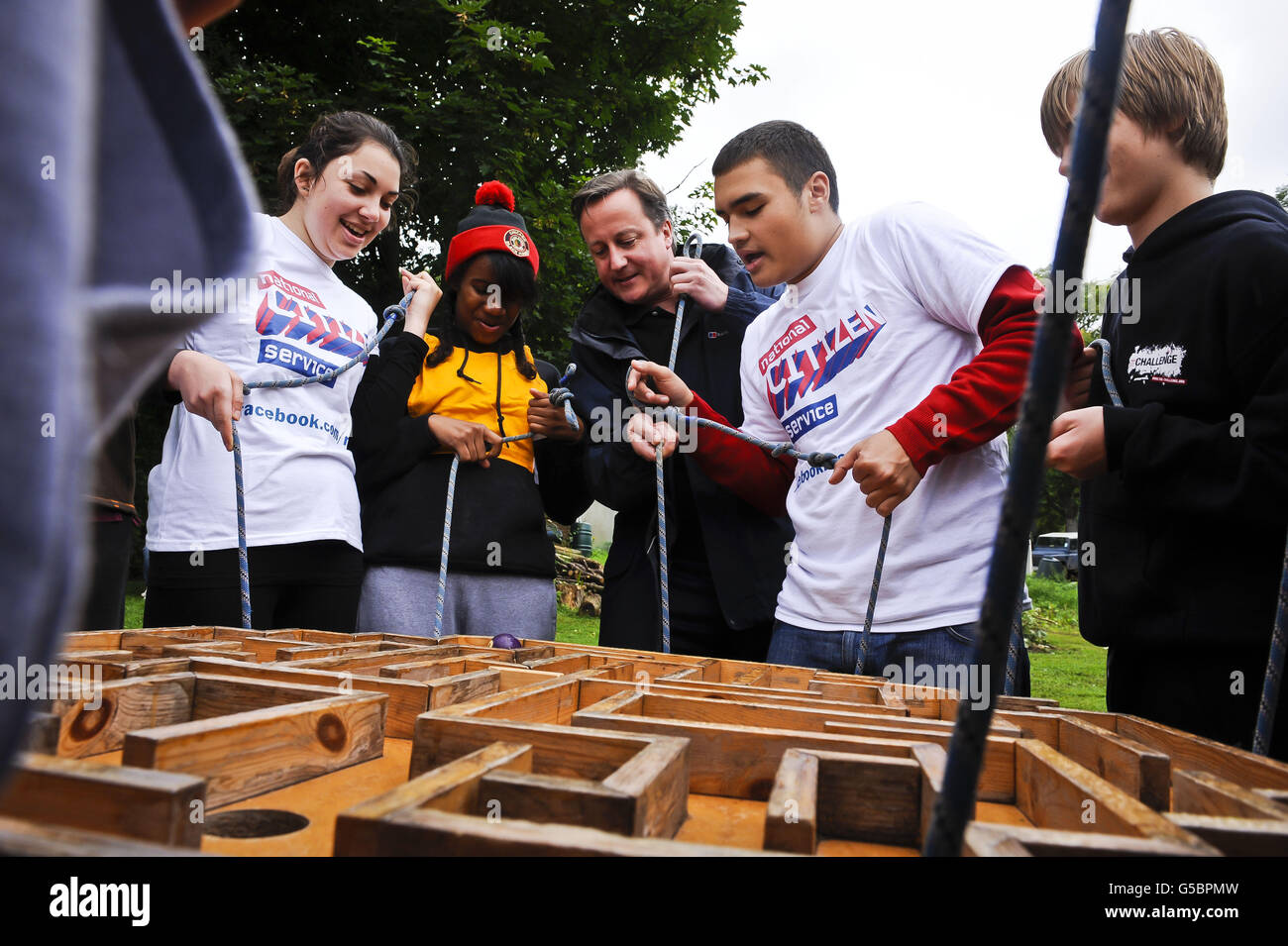 Le Premier ministre David Cameron prend part à un casse-tête de construction d'équipe où les jeunes du programme national de services aux citoyens participent à des exercices de renforcement d'équipe, à l'installation d'éducation de plein air, à Gilwern, au pays de Galles. Banque D'Images