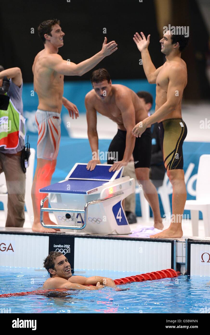 Les USA Michael Phelps (dans la piscine), Conor Dwyer (à gauche), Ryan Lochte (au centre) et Ricky Berens (à droite) célèbrent après avoir remporté la finale du Relais Freestyle de 4 x 200 m au Aquatics Center dans le Parc olympique au cours du quatrième jour des Jeux olympiques de Londres 2012. Banque D'Images