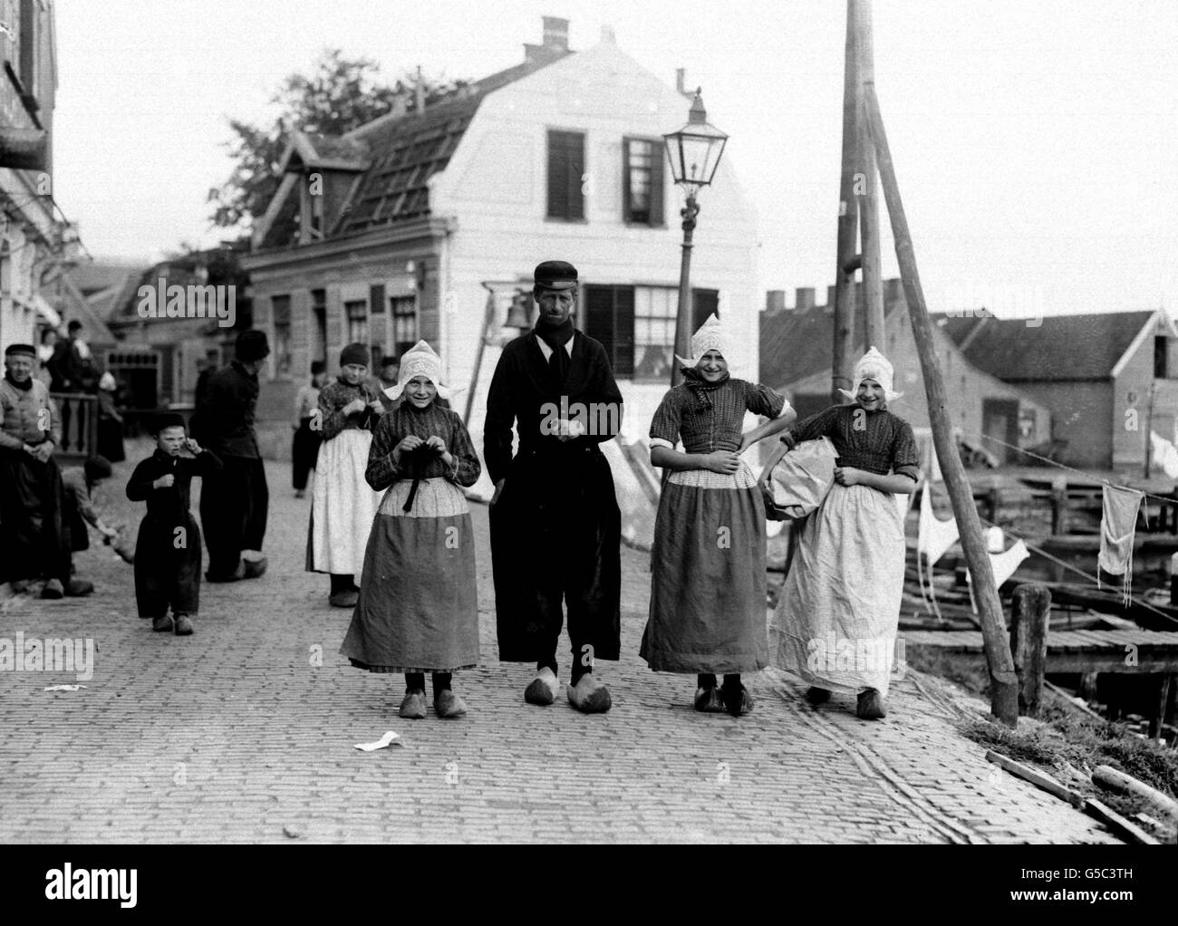 PAYS-BAS 1910: Pêcheurs portant une robe traditionnelle, y compris des sabots et des casquettes en dentelle, dans le port hollandais de Volendam. Banque D'Images