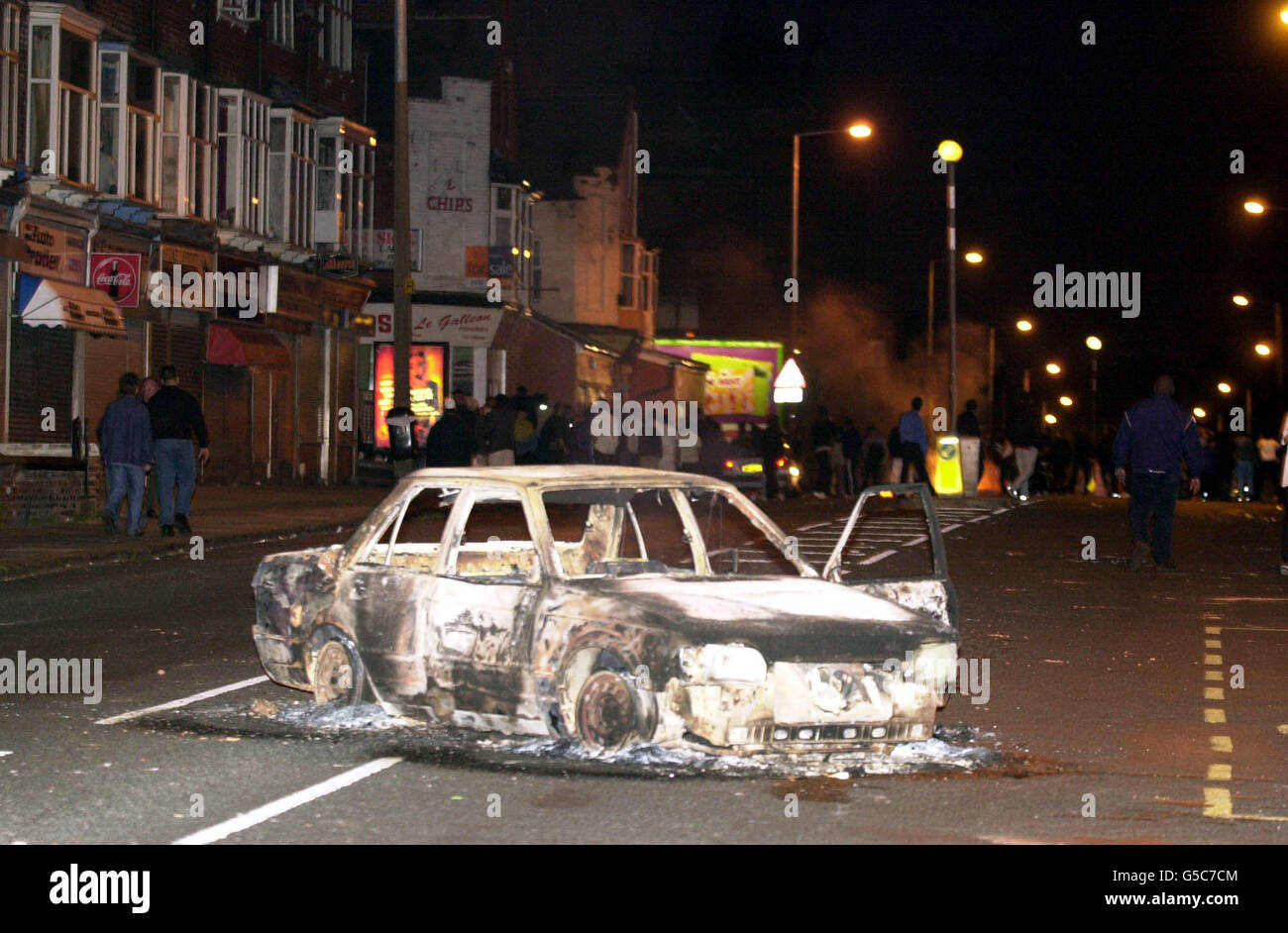 Une voiture brûlée à Leeds après que des centaines de émeutiers asiatiques ont envahi les rues pour mettre des voitures et jeter des briques.Après une pause de deux heures au cours de laquelle la police avait gardé ses distances, les ennuis se sont à nouveau déclarés lorsque les policiers anti-émeutes et les chiens de police ont pris le dessus. Banque D'Images