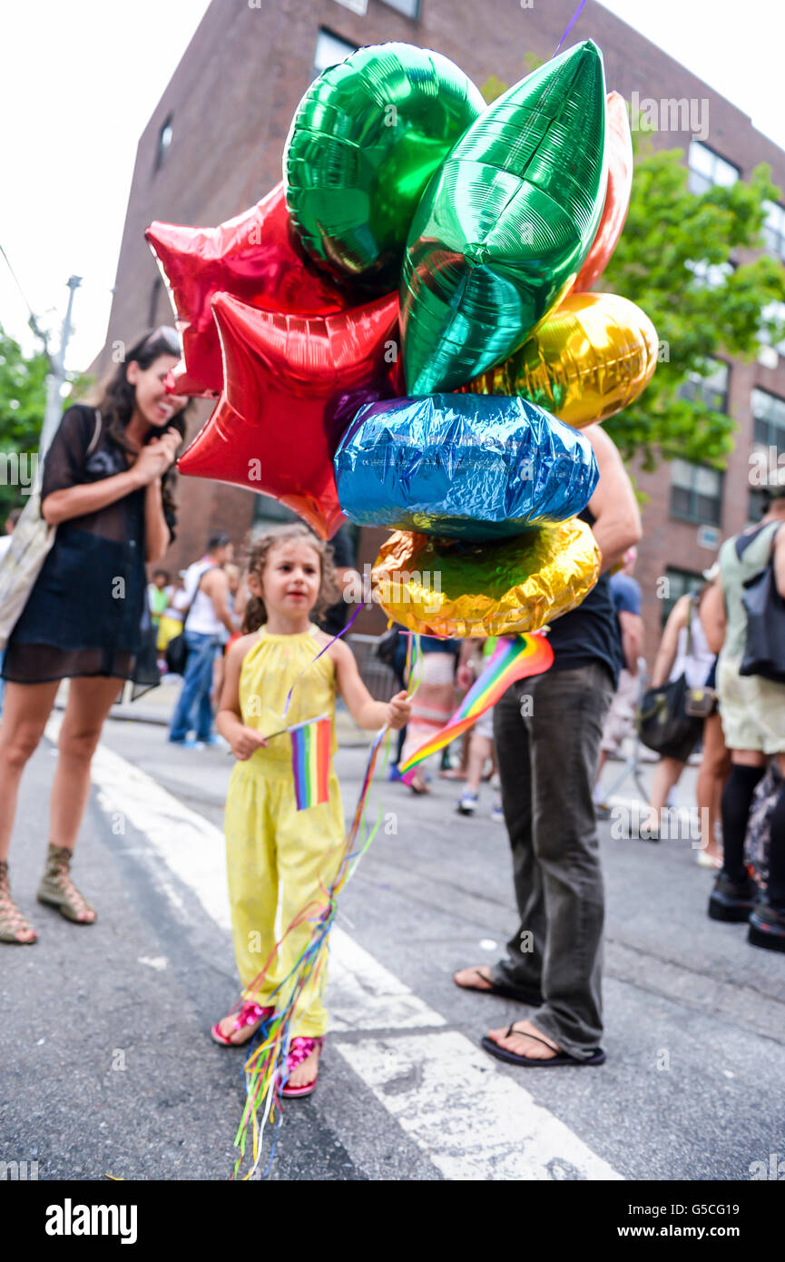 NEW YORK - 30 juin 2013 : un enfant est titulaire d'un drapeau arc-en-ciel et un bouquet de ballons colorés à l'assemblée annuelle gay Pride Festival. Banque D'Images