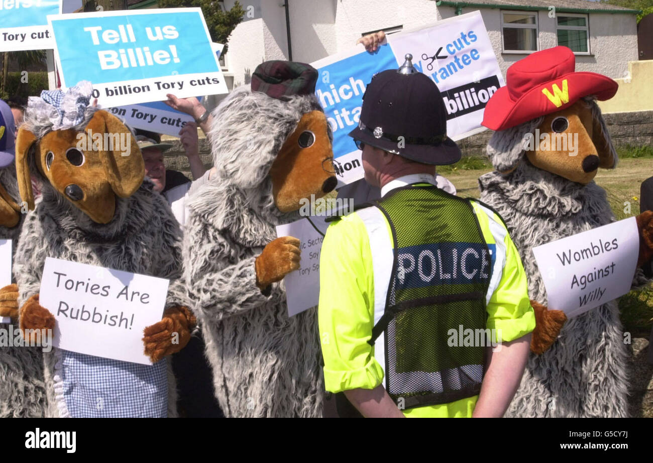 Les gens déguisés en personnages de dessin animé pour enfants, les Wombles, protestent contre d'éventuelles suppressions d'emplois, si les Tory entrent au pouvoir, comme le chef du Parti conservateur William Hague en parle avec les militants du parti local à Helston, regarde sur la piste de campagne électorale générale à Cornwall. Banque D'Images