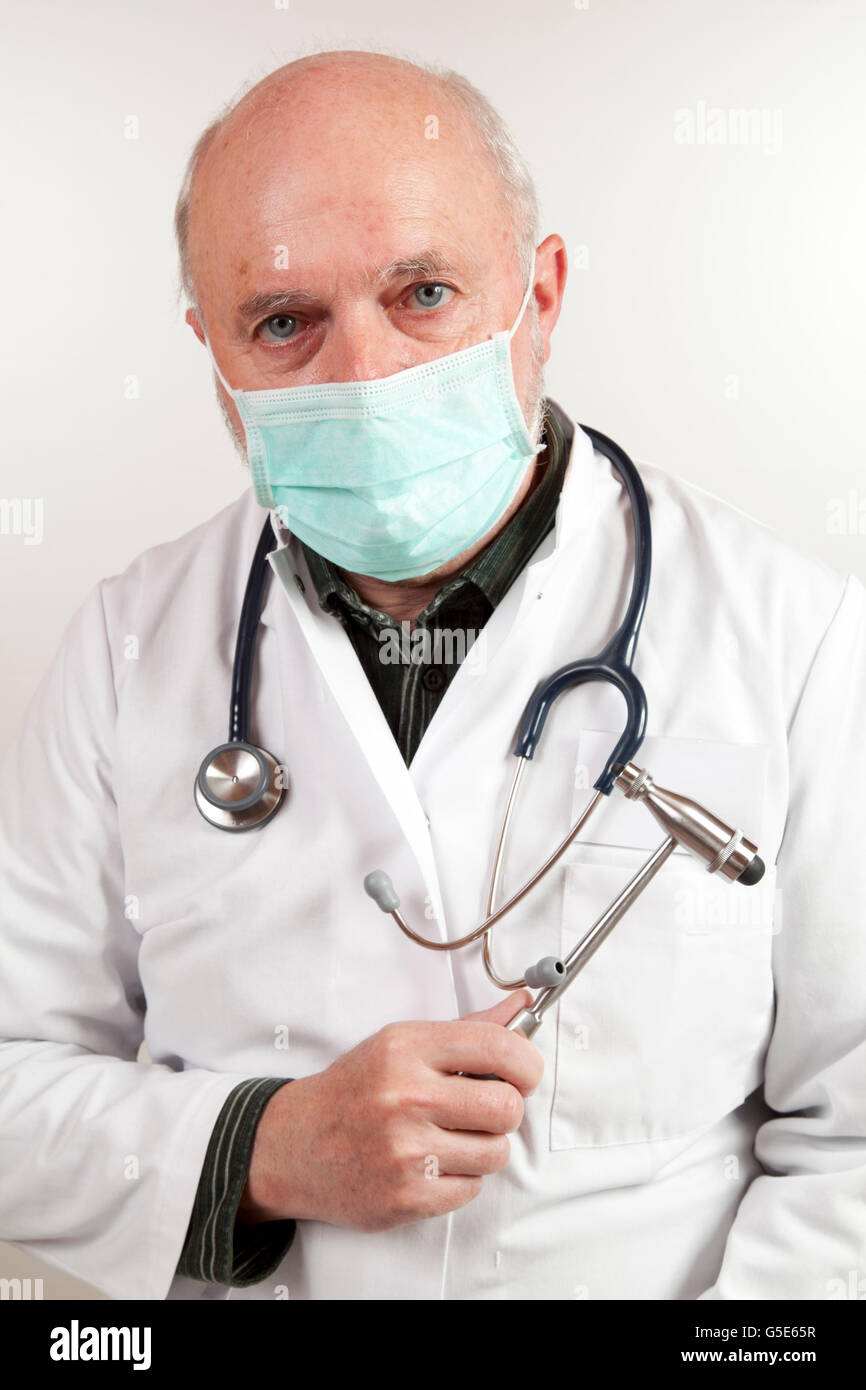 Un homme âgé, médecin portant des masques chirurgicaux, avec un stéthoscope et un marteau à réflexe Banque D'Images