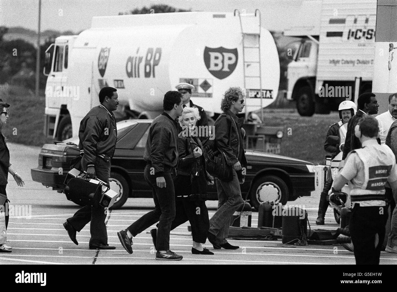 La chanteuse et actrice américaine Madonna (au centre, en face de l'appareil photo) arrive à l'aéroport de Leeds Bradford, sur le chemin de son premier concert britannique à Roundhay Park, à Leeds. Banque D'Images