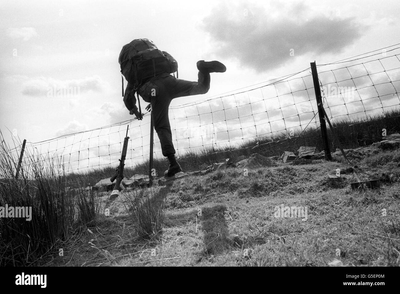 Une recrue SAS pour l'aile territoriale s'attaque à une clôture, pondérée avec un pack de 45 lb, lors de marches d'endurance dans les Brecon Beacons, au pays de Galles. Banque D'Images