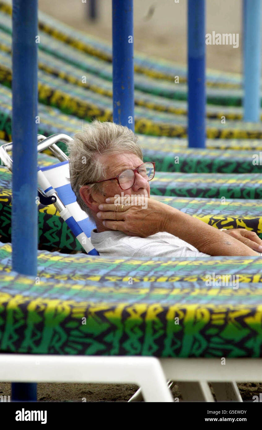 Un homme est assis près de la plage sur la Costa Del sol, tandis que les touristes britanniques de Torremolinos souhaitaient avoir séjourné au Royaume-Uni. Les tentures ont atteint les années 30 en Grande-Bretagne, tandis qu'en Espagne, le temps a été couvert après les averses. Banque D'Images