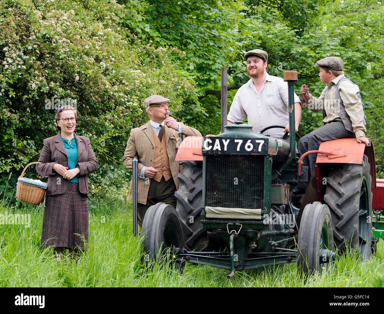 Le Squire et une dame plus âgée en 1940, l'habillement parlant à un agriculteur et farm boy sur tracteur Fordson Major. NB WW2 re-eneactment. Banque D'Images