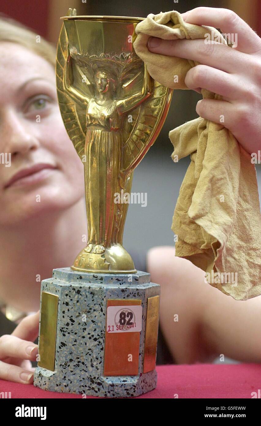Rachel Dewhurst de Christie's détient une réplique en métal jaune du trophée  Jules Rimet devant les casquettes d'Angleterre remportées par Sir Alf  Ramsey, directeur de l'équipe gagnante de la coupe du monde