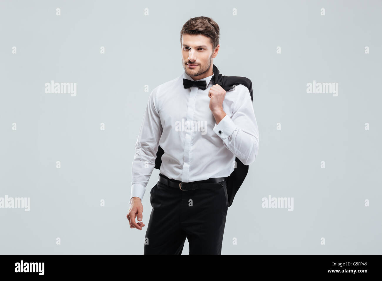 Handsome young man in tuxedo avec bowtie holding sa veste Banque D'Images