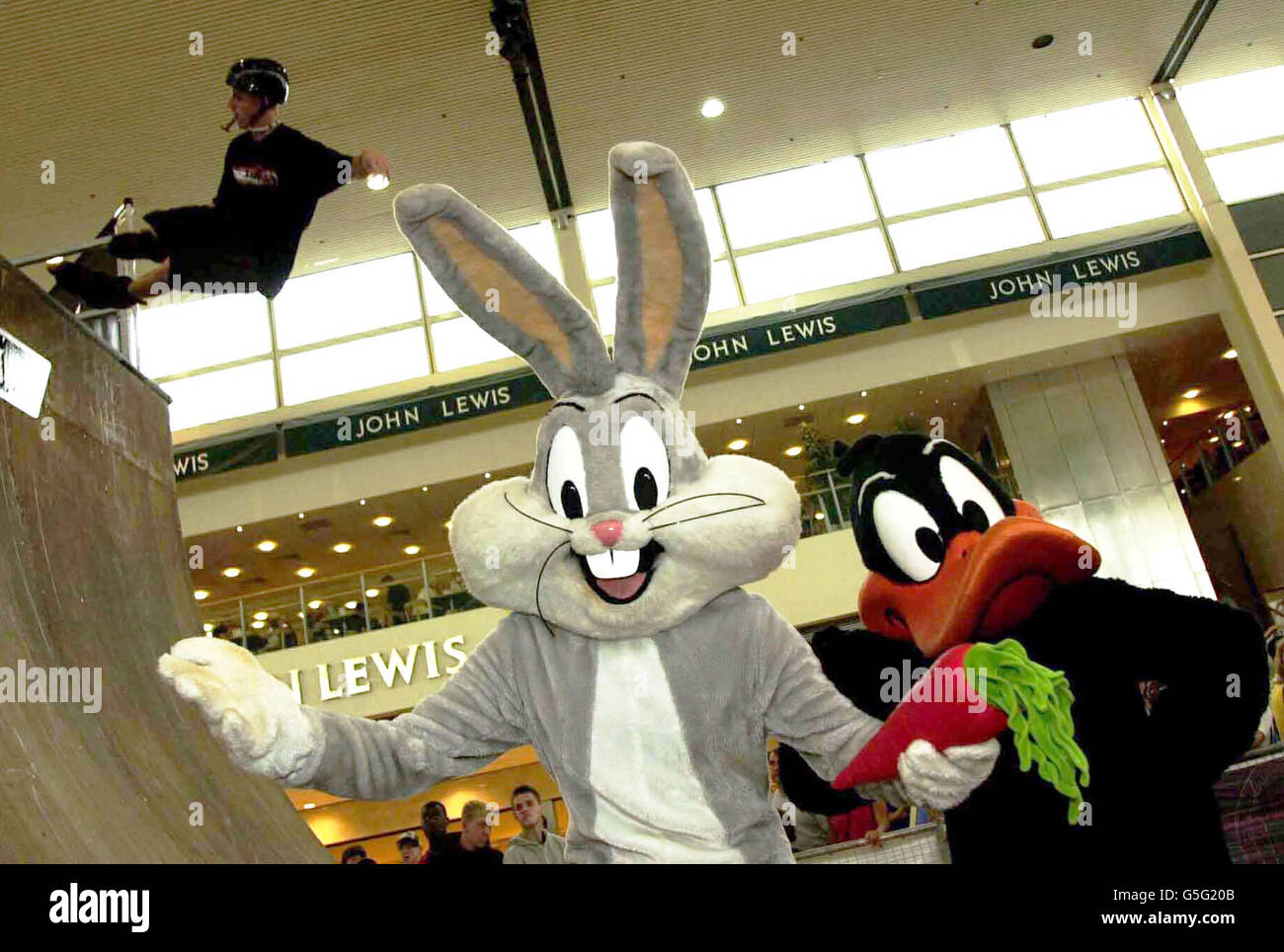Un patineur en ligne montre ses tours au village de patins de Looney Tunes, Milton Keynes, regardé par les personnages de dessins animés Bugs Bunny (L) et Daffy Duck. Banque D'Images