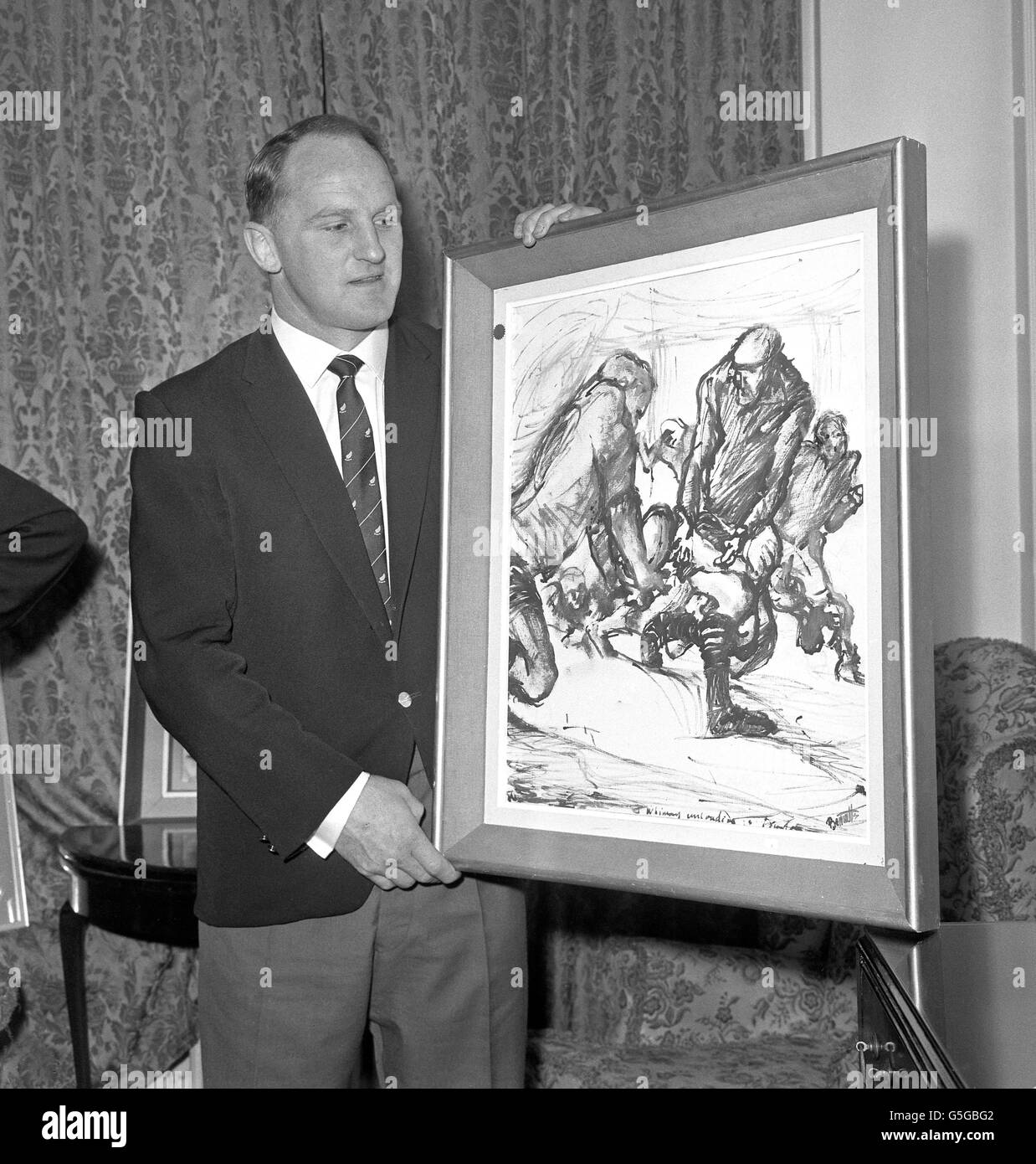 Wilson Whineray, capitaine des All Blacks de Nouvelle-Zélande, reçoit un dessin au Park Lane Hotel de Londres. L'image, « Whineray passant à Meads » par l'artiste Kenneth Bennetts, est un cadeau de cinq hommes d'affaires néo-zélandais travaillant en Grande-Bretagne. Banque D'Images