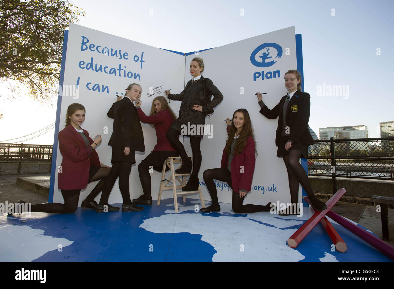 Présentatrice Cherry Healey (au centre) avec des filles de l'école St Cecilia à Southfields, Evie Edgar, 14 (à gauche), Emily Craig, 14 (à gauche), Ellie Guven, 14 (à droite) et de l'école Graveney à Tooting, Hannah Davis, 13 (à gauche) et Tilly Holmes, 14 (à droite), Ils contribuent à sensibiliser la population à la première Journée internationale de la fille en signant le livre de Plan UK intitulé « parce que je peux » à la Tour de Londres. Banque D'Images