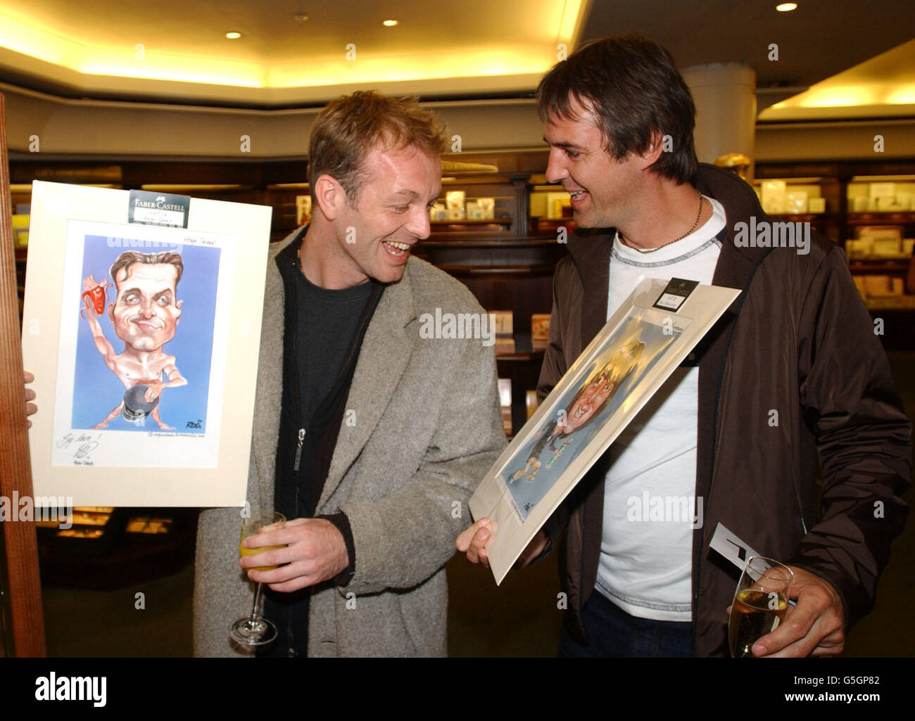 Les acteurs Neil Morrissey (à droite) et Hugo Spear comparent des dessins lors d'une vente aux enchères de caricatures de stars dans l'aide de War Child après le lancement des derniers dessins du styliste Faber-Castell à Harrods à Londres. Banque D'Images