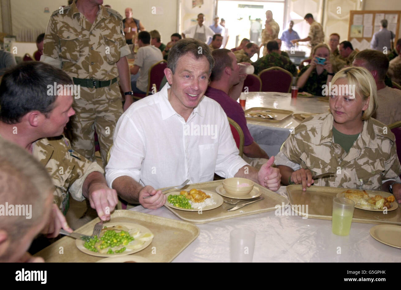 Le Premier ministre britannique Tony Blair visite les troupes britanniques en exercice à Oman. M. Blair a rejoint les troupes dans un mess de fortune pour un déjeuner de curry, de riz et de pois. *...et est assis avec le caporal Lynn Stevenson (R) du 30 signal Regiment basé à Nuneaton et Paul Taylor, normalement basé à Tidworth, Wiltshire. M. Blair a effectué une visite de la base Al Sha'afa, le centre de commandement de l'opération Swift Sword II, impliquant plus de 20,000 militaires britanniques dans le plus grand déploiement depuis la guerre du Golfe. Banque D'Images