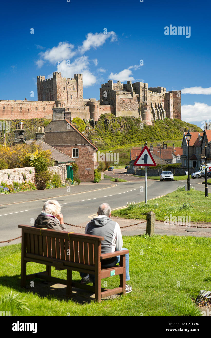 Royaume-uni, Angleterre, Bamburgh Northumberland, couple sur banc admirant château du village green Banque D'Images