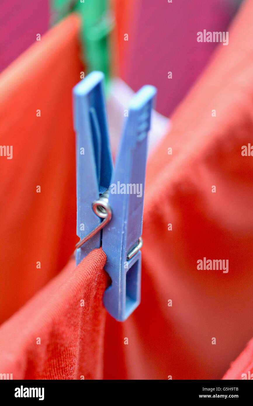 Clothespin sur corde de fixation du red vêtements mouillés. Les vêtements humides rouge séchage sur corde en la fixant avec clothespin. Banque D'Images