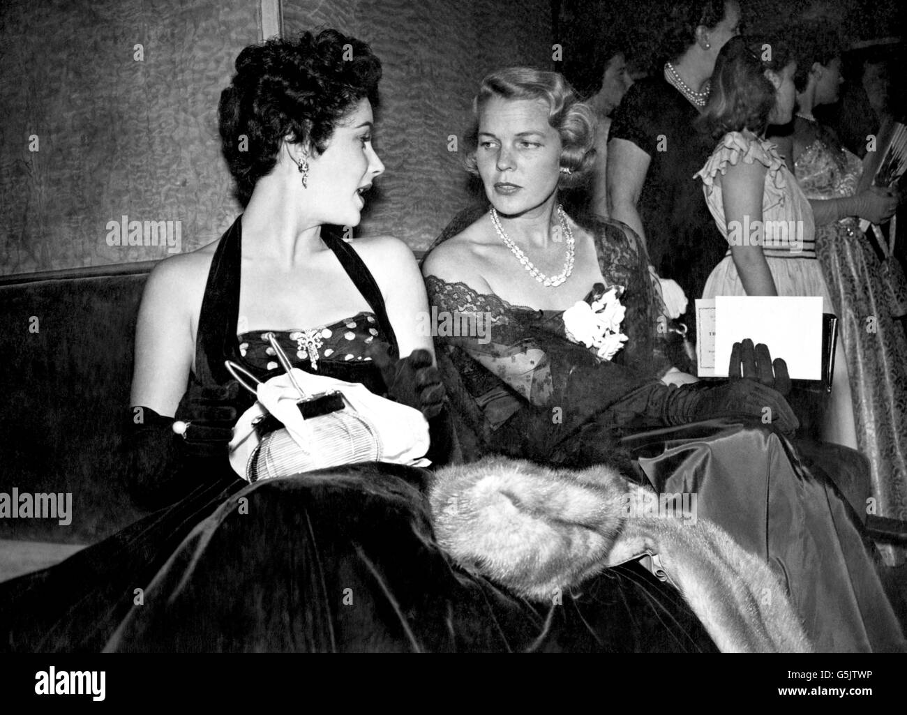 Elizabeth Taylor, star hollywoodienne (à gauche) discutant avec un ami au Warner Theatre, avant la première mondiale du film britannique The Lady with the Lamp. Banque D'Images