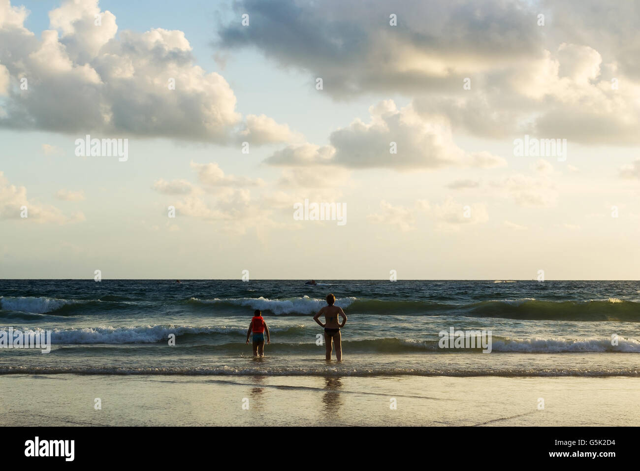 Seascape avec certaines personnes vous détendre sur la plage coucher du soleil dans la lumière du soir Banque D'Images