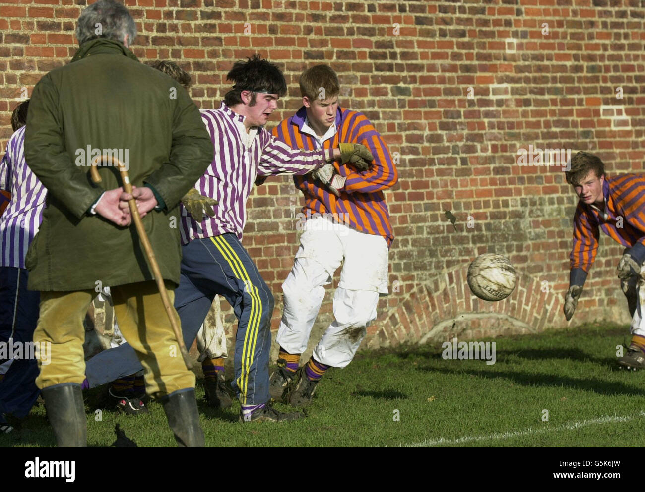 Une montre officielle (à gauche) asPrince Harry, 17, (au milieu) lutte pour le ballon pendant le jeu annuel de mur d'Eton de jour de St. Andrew, à Eton College, Berkshire. Banque D'Images