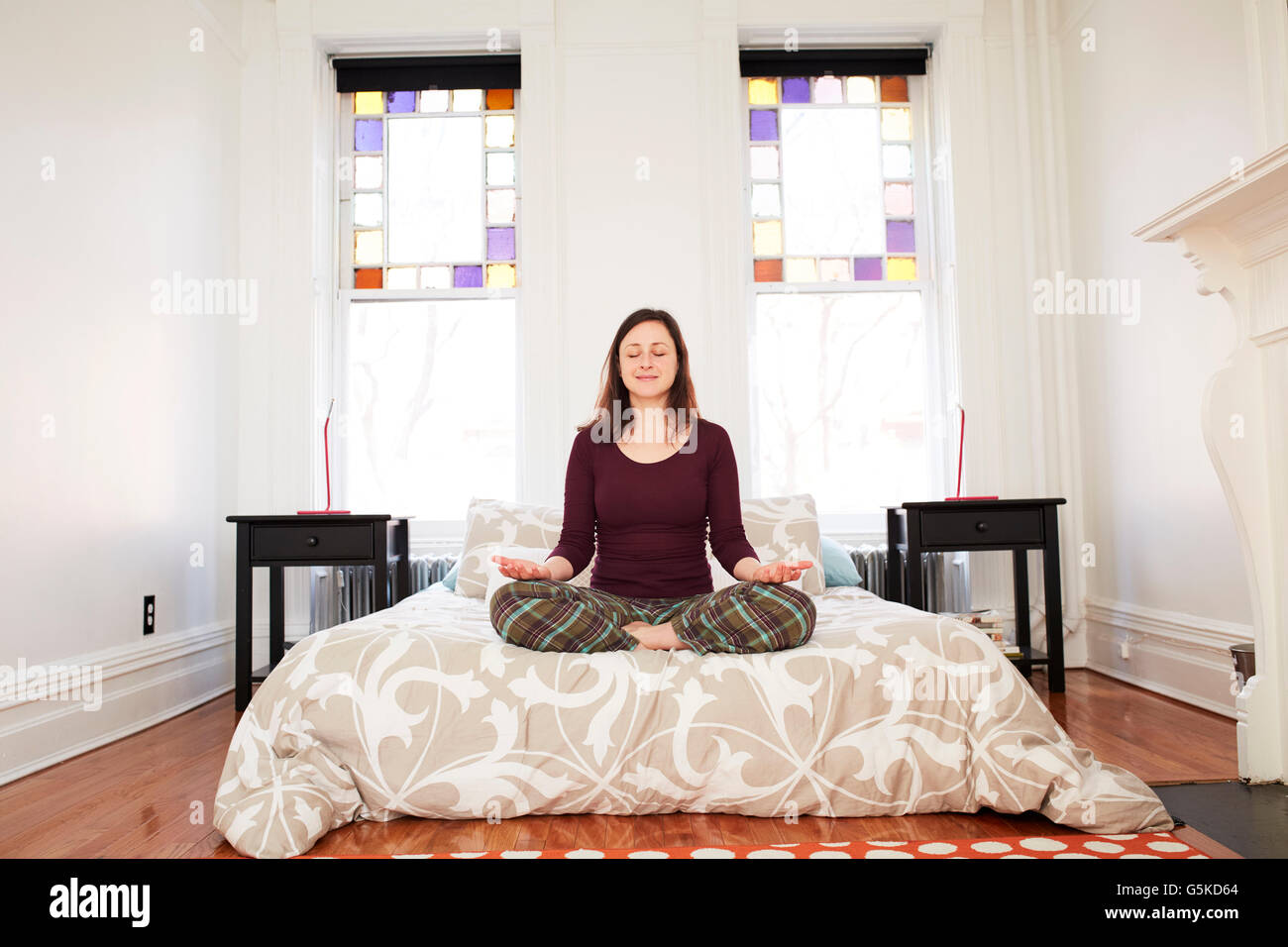 Mixed Race woman meditating in bedroom Banque D'Images