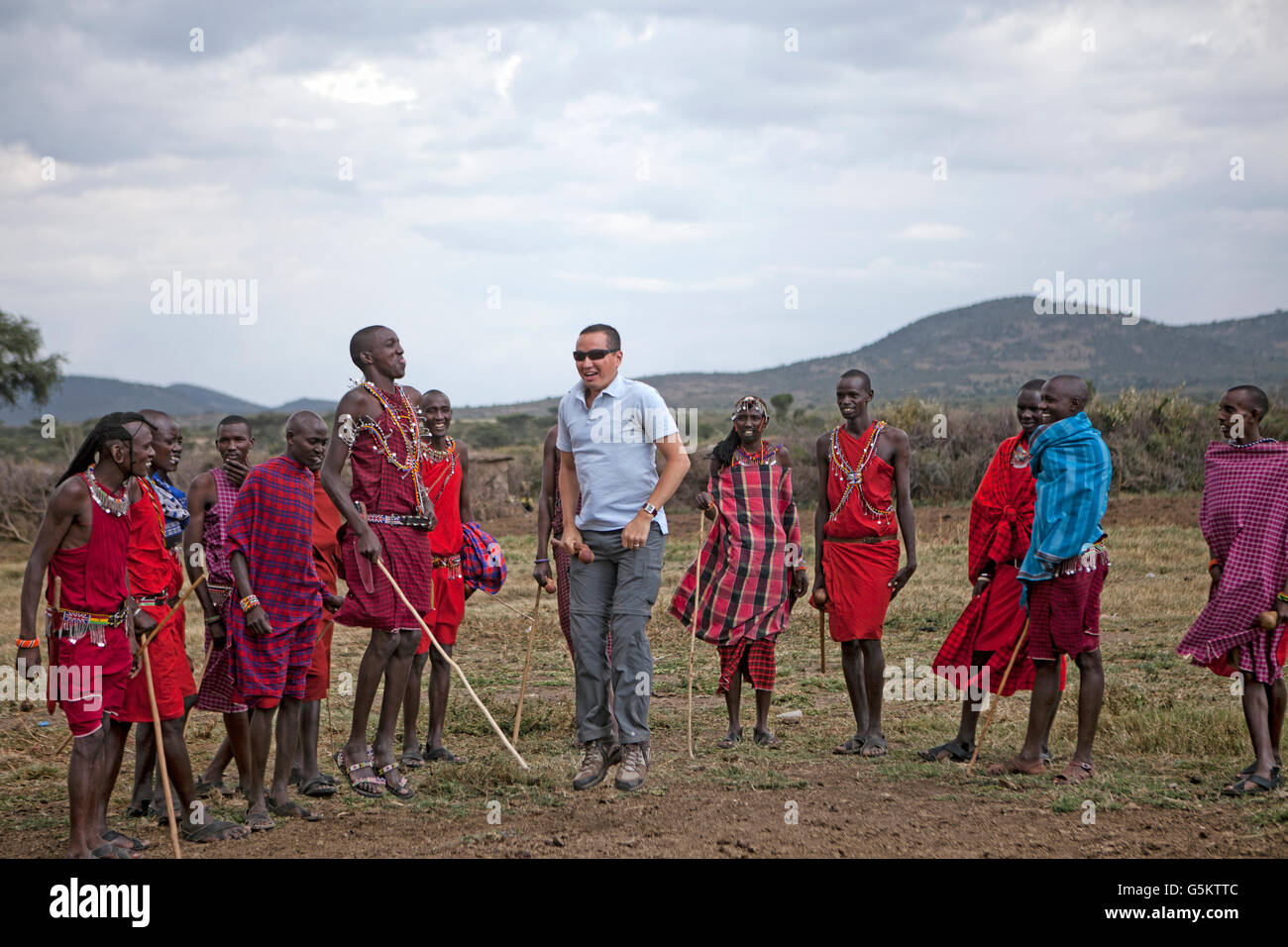 Groupe de guerriers Masai et un touriste faisant une danse de cérémonie dans un Maaai village, Kenya, Afrique. Banque D'Images