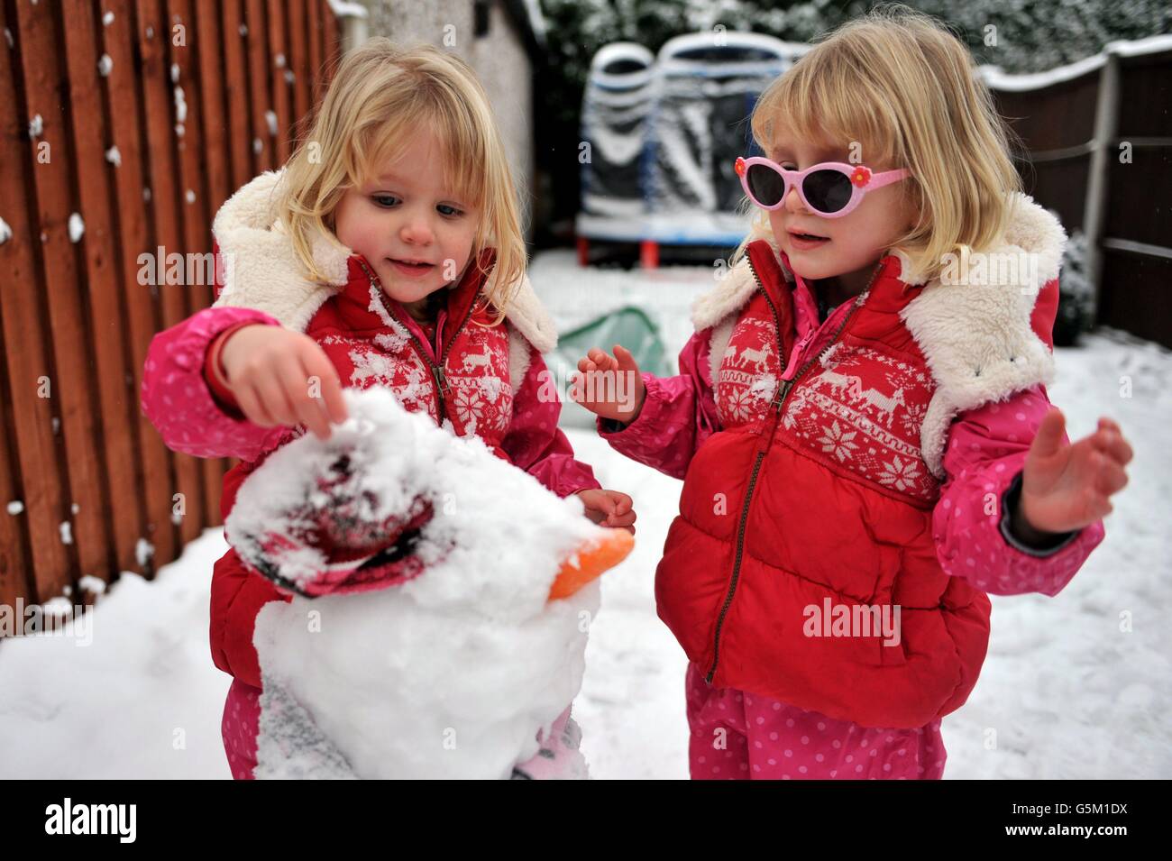 Les sœurs jumelles Maddie (à gauche) et Grace Wilson ont mis la touche finale à leur bonhomme de neige à long Eaton, dans le Notinghamshire. Des milliers d'enfants ont obtenu une journée de congé supplémentaire, alors que les écoles étaient fermées et que les conditions météorologiques hivernales se sont poursuivies dans tout le Royaume-Uni. Banque D'Images