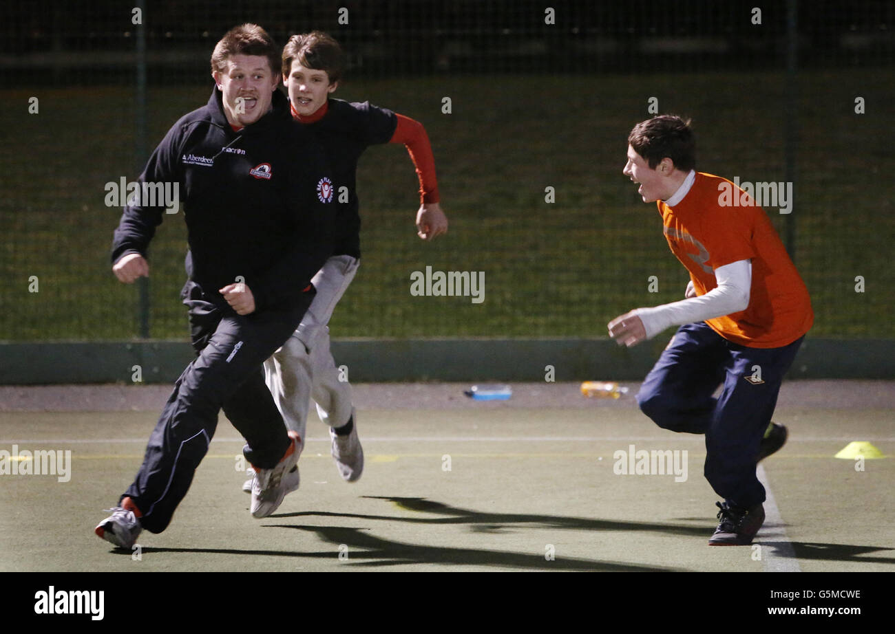 Alun Walker d'Edinburgh Rugby avec des enfants de l'école secondaire Ross lors d'une journée de rugby à tête noire où des membres de l'équipe de joueurs ont donné des séances de rugby aux enfants de l'école, à Ross High, East Lothian. Banque D'Images