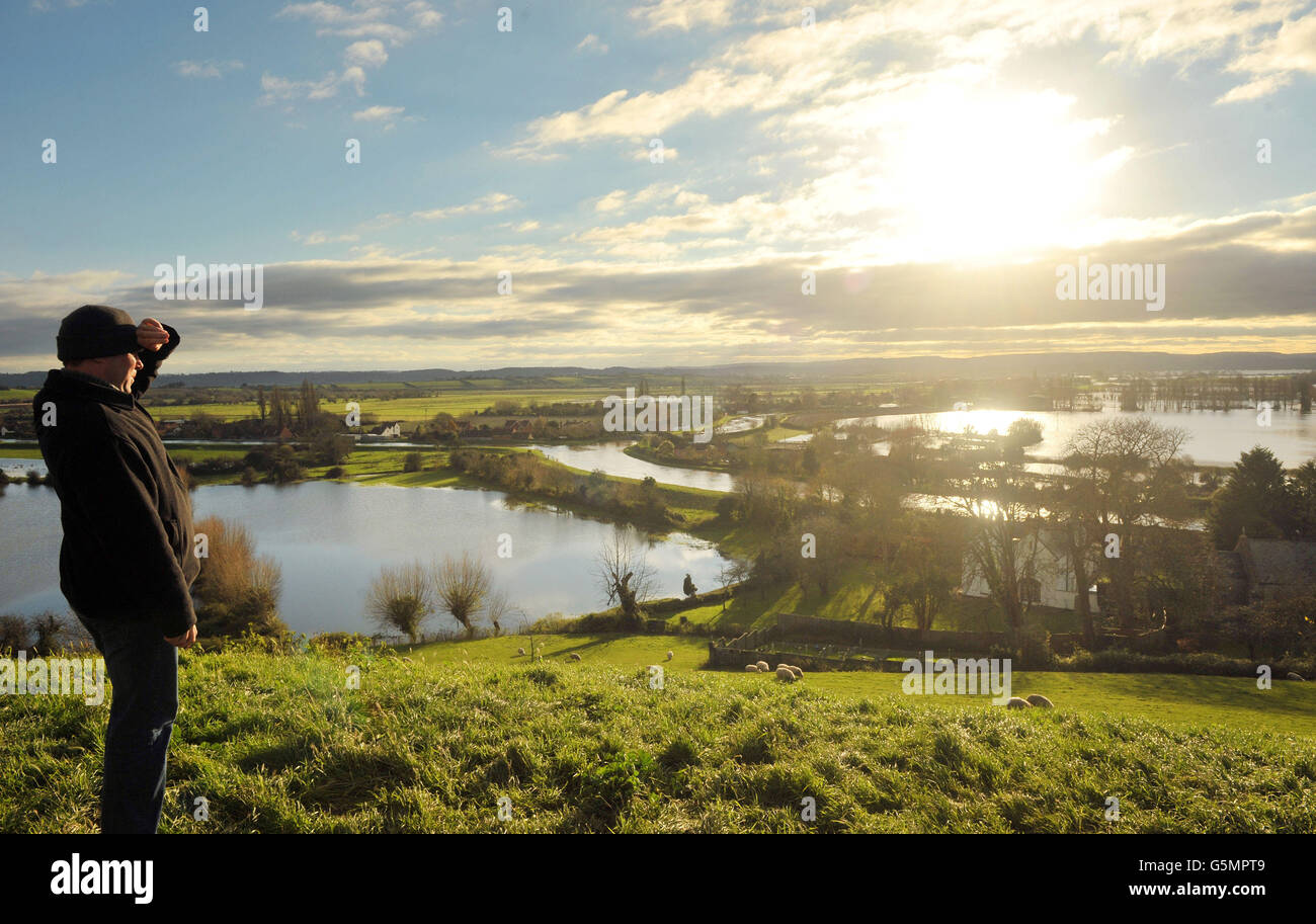 Un homme regarde sur les eaux de crue dans le Somerset depuis Burrow Mump, car les niveaux d'eau restent élevés malgré une journée sèche. Banque D'Images