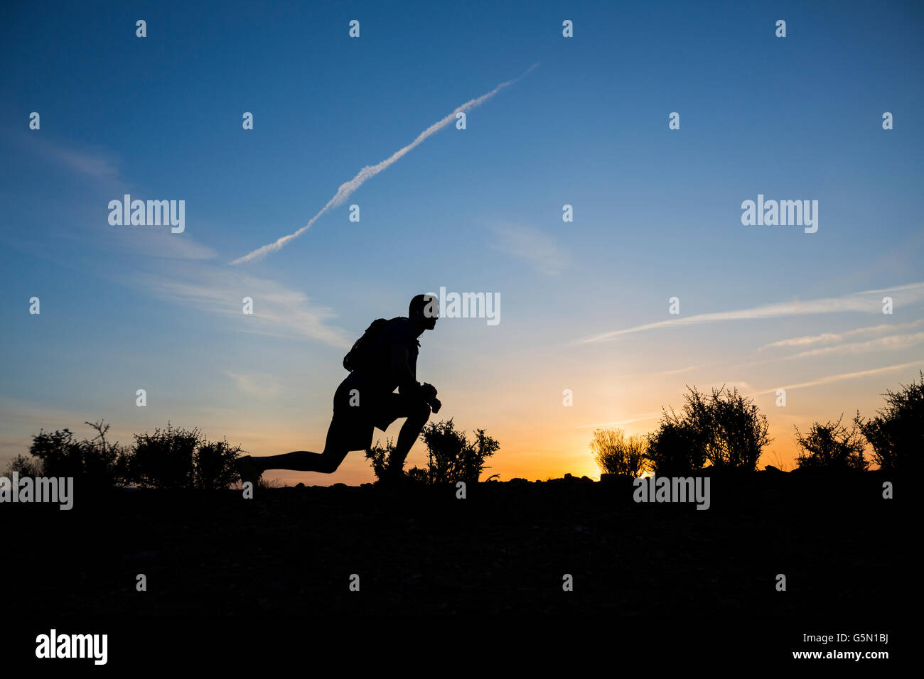 Silhouette of Caucasian teenage boy running at dawn Banque D'Images