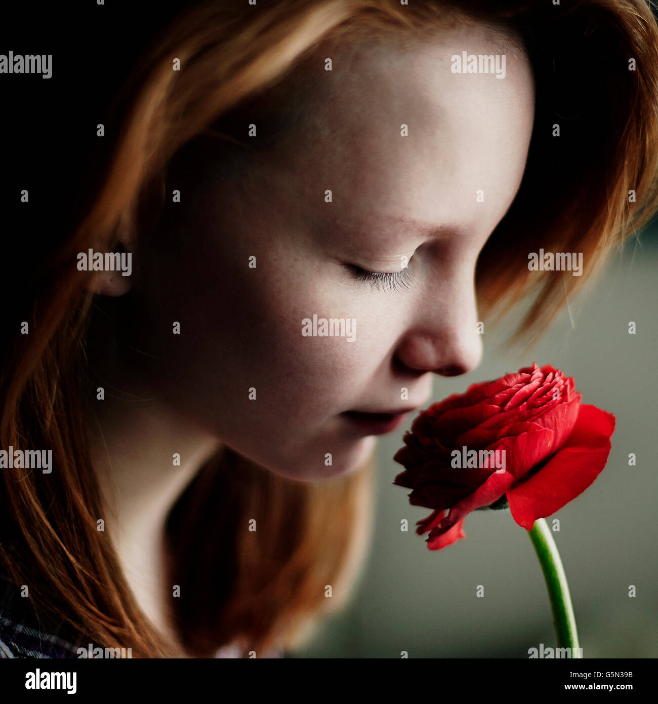 Caucasian teenage girl smelling flower Banque D'Images