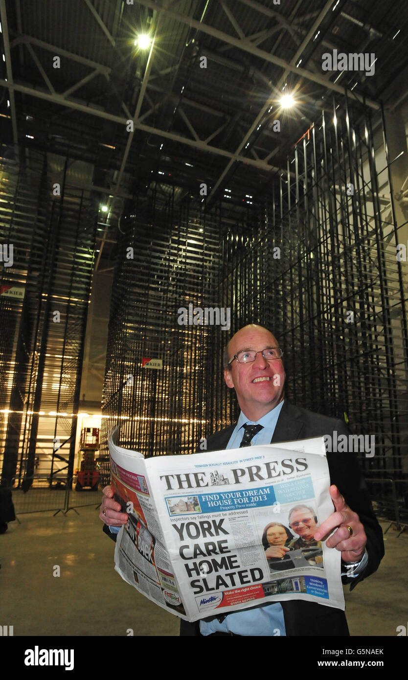 Steve Morris, de la British Library, détient une copie du journal local, comme il se trouve parmi les rayonnages dans le nouveau bâtiment de stockage de journaux de la British Library à Boston Spa, Wetherby, West Yorkshire. Banque D'Images