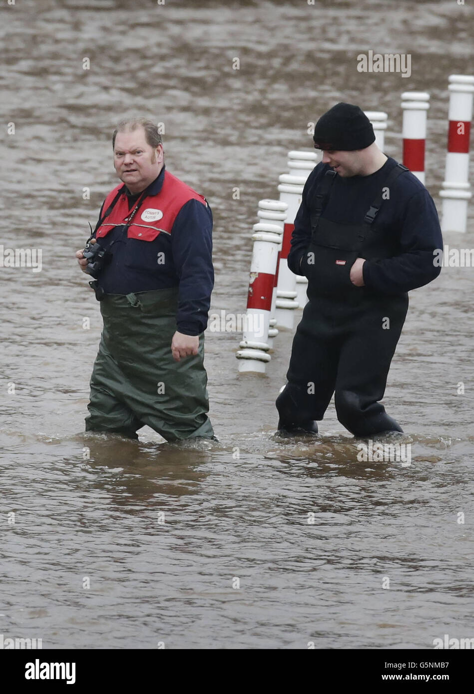 Des hommes traversent les eaux d'inondation à Cupar, en Écosse, après que la rivière Eden a éclaté ses berges après une forte pluie continue. Banque D'Images