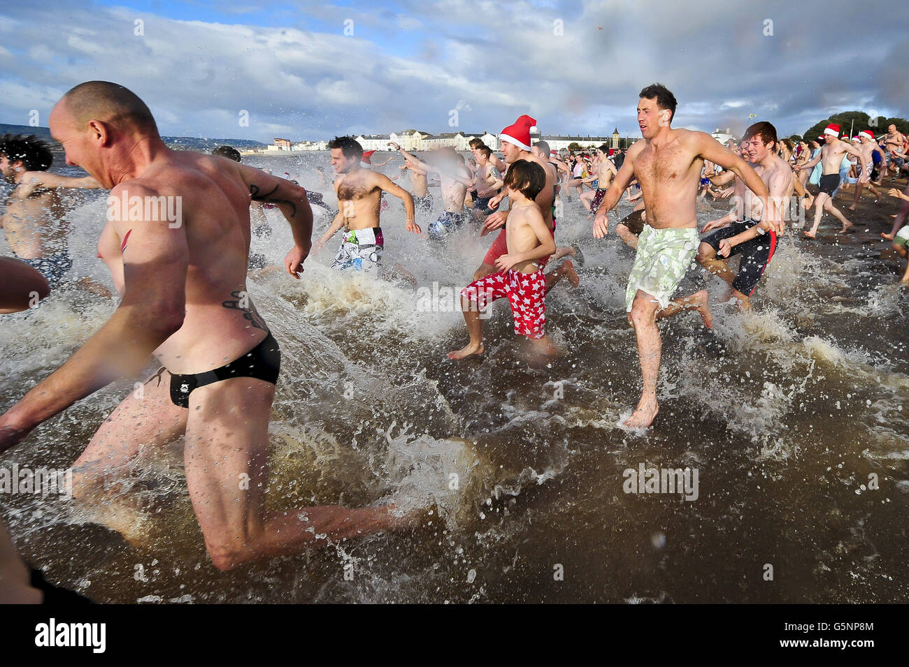 Les nageurs prennent la mer à Exmouth pour la baignade annuelle du jour de Noël. Banque D'Images