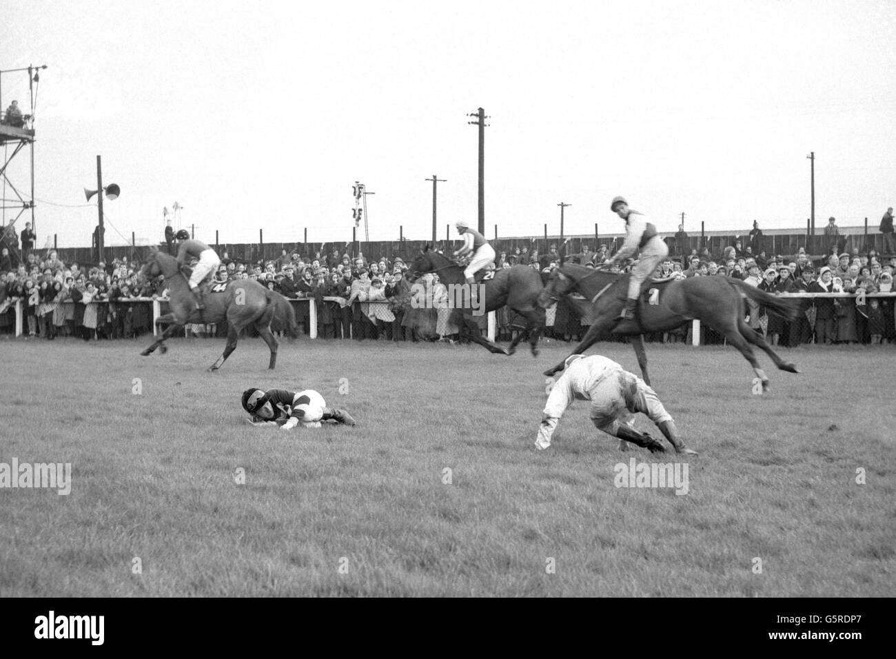 T. Carberry, un jockey tombé, qui était à cheval 'Packed' et G. W. Robinson, qui était à cheval 'Popham Down', se ramassent après être tombé à Becher's Brook. Passant est le cheval japonais 'Jujino-o', J. King up. Banque D'Images