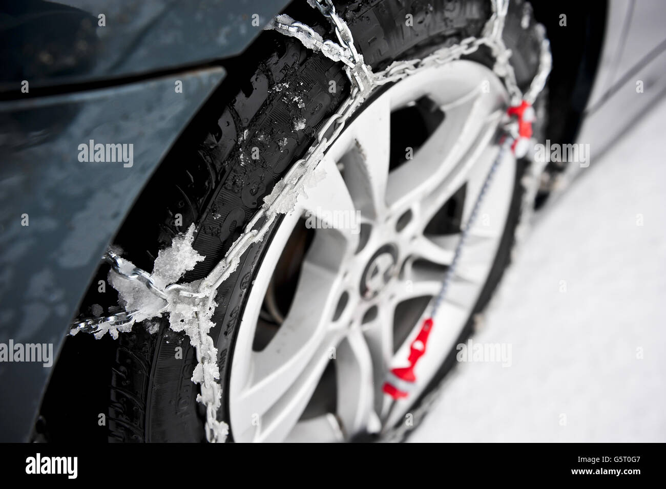 LES chaînes à neige THULE CG-9 sont montées et auto-tendues sur la roue motrice arrière d'une BMW. Les chaînes à neige facilitent la conduite dans la neige, en particulier sur les véhicules à propulsion arrière, qui sont beaucoup plus enclins à se coincer en raison d'une perte de traction. Banque D'Images