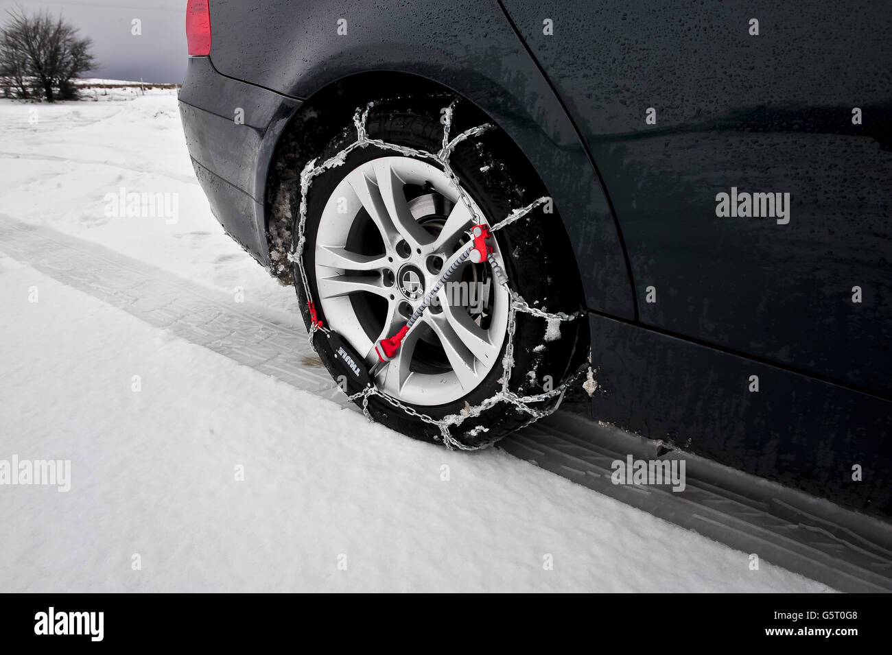 LES chaînes à neige THULE CG-9 sont montées et auto-tendues sur la roue motrice arrière d'une BMW. Les chaînes à neige facilitent la conduite dans la neige, en particulier sur les véhicules à propulsion arrière, qui sont beaucoup plus enclins à se coincer en raison d'une perte de traction. Banque D'Images