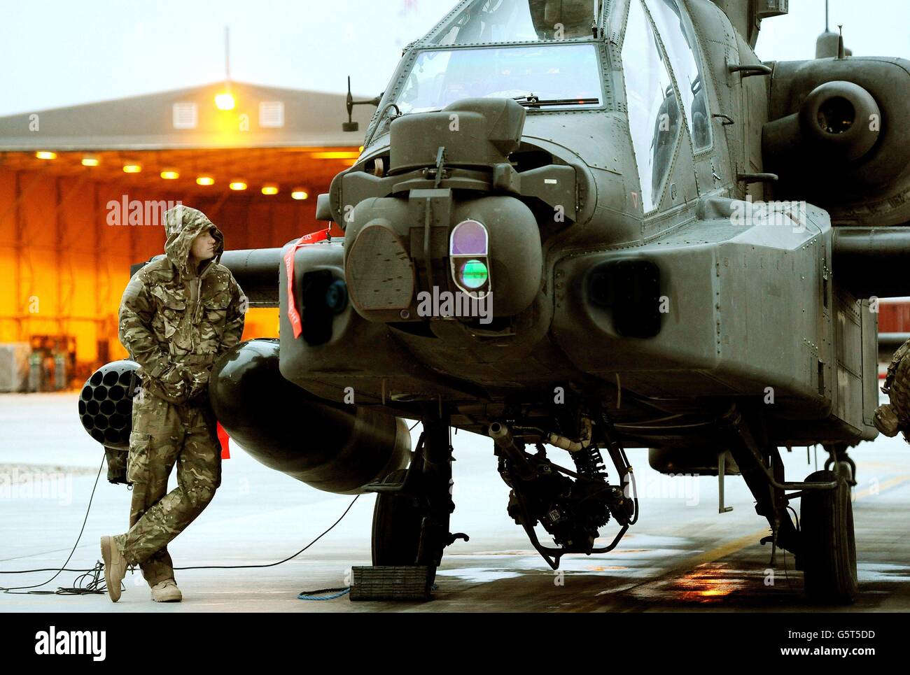 CERTAINES PARTIES DE CETTE IMAGE ONT ÉTÉ MODIFIÉES NUMÉRIQUEMENT POUR DES RAISONS DE SÉCURITÉ. Photo précédemment non publiée du 12/12/2012 du prince Harry ou du simple capitaine Wales, connu dans l'armée britannique, effectuant ses contrôles avant vol tôt le matin sur la ligne de vol, au camp Bastion, dans le sud de l'Afghanistan, où il sert comme pilote d'hélicoptère Apache/Gunner avec 662 corps d'aviation de l'armée SQD, De septembre 2012 pour quatre mois jusqu'à janvier 2013. Banque D'Images