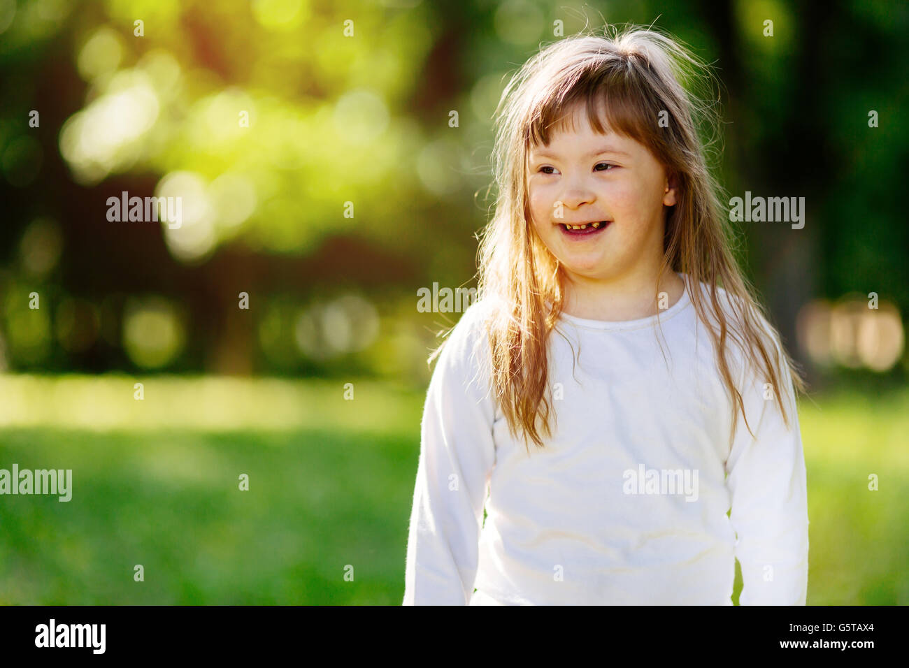 Belle heureux enfant souffrant de syndrome de Down smiling outdoors Banque D'Images