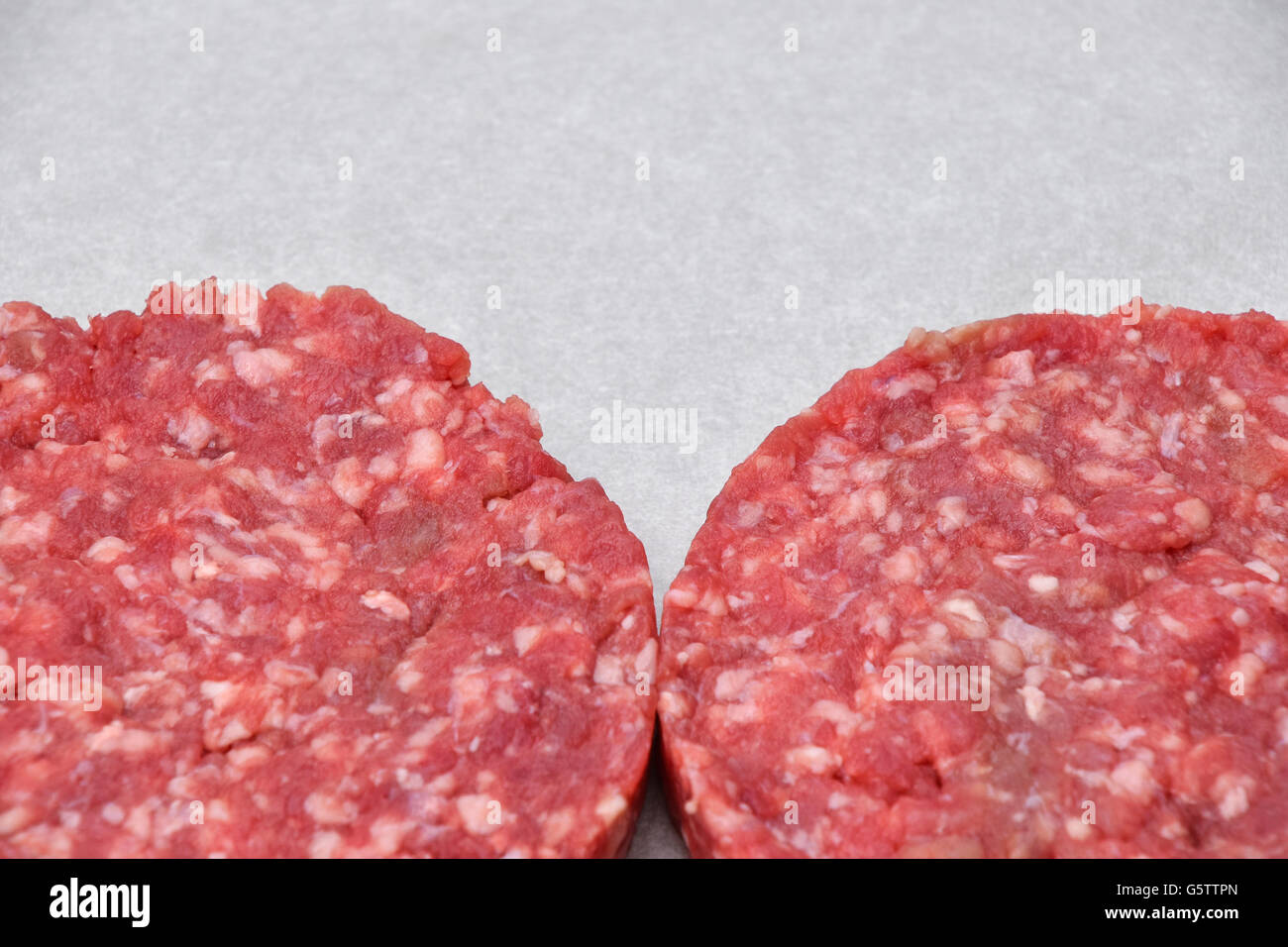 La viande rouge des hamburgers pour hamburgers de viande hachée de boeuf ou porc sur du papier parchemin blanc prêt pour la cuisson Banque D'Images