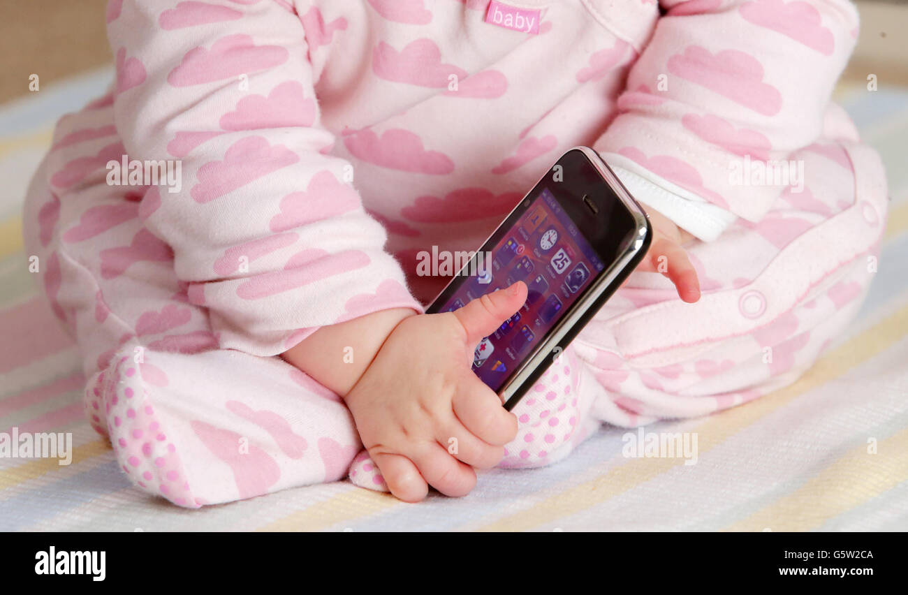 STOCKER bébé. Un bébé tenant un iPhone 3GS d'Apple. Banque D'Images