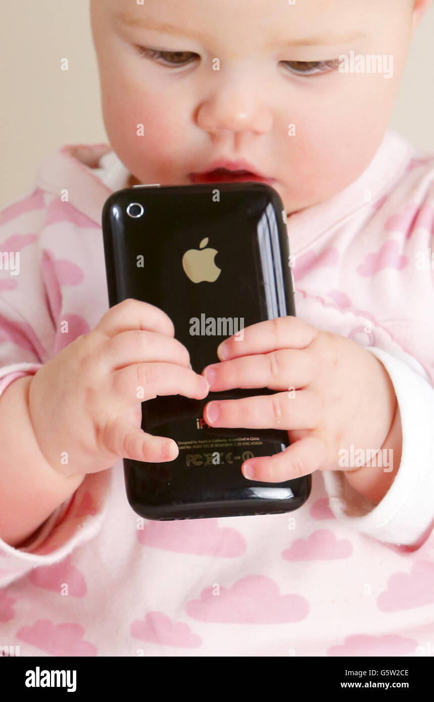STOCKER bébé. Un bébé tenant un iPhone 3GS d'Apple. Banque D'Images
