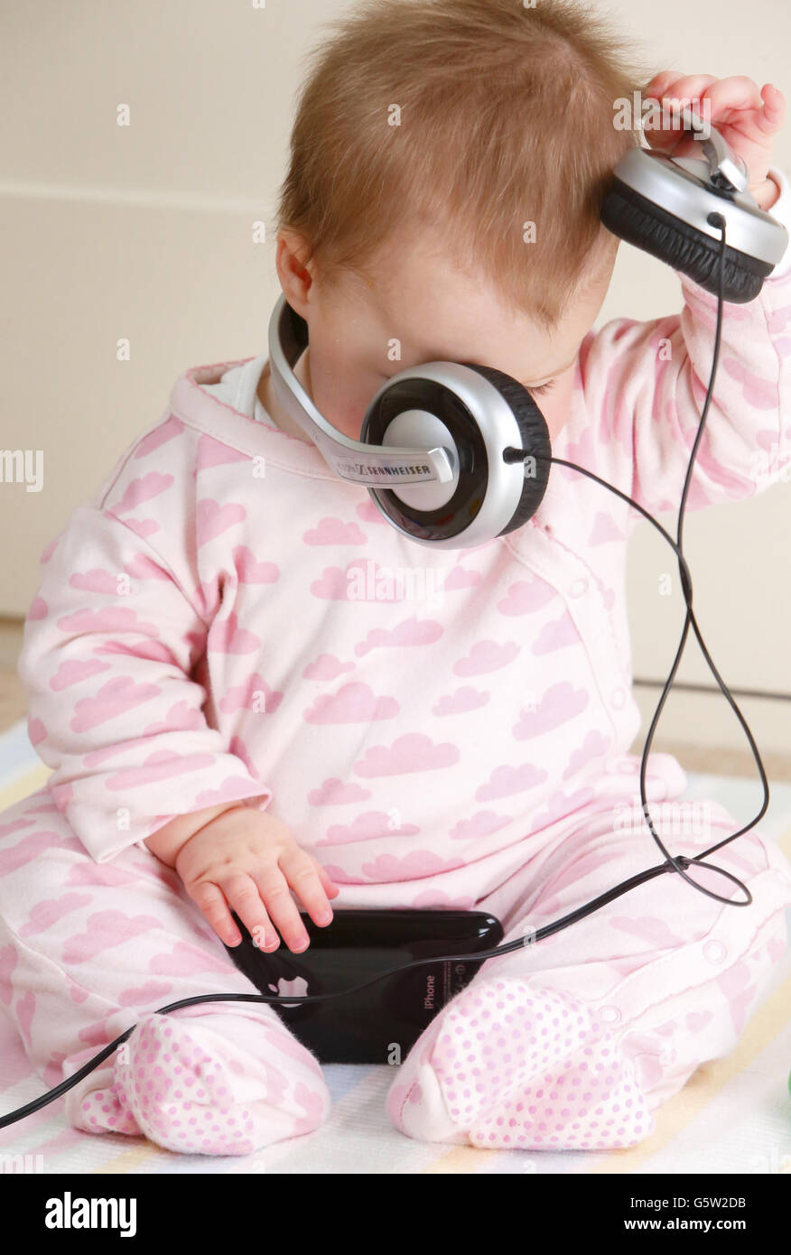 STOCKER bébé.Un bébé portant un casque et tenant un iPhone 3GS d'Apple. Banque D'Images