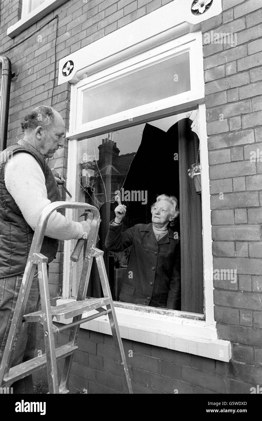 Alice Howarth, 69 ans, et un vitrier inspectent l'une de ses fenêtres, qui a été endommagée lorsque la violence a éclaté sur Ivy Road alors que les fans ont quitté le match Luton Town and Millwall. La cravate FA Cup a été interrompue lorsque les fans de Millwall ont envahi le terrain. Banque D'Images