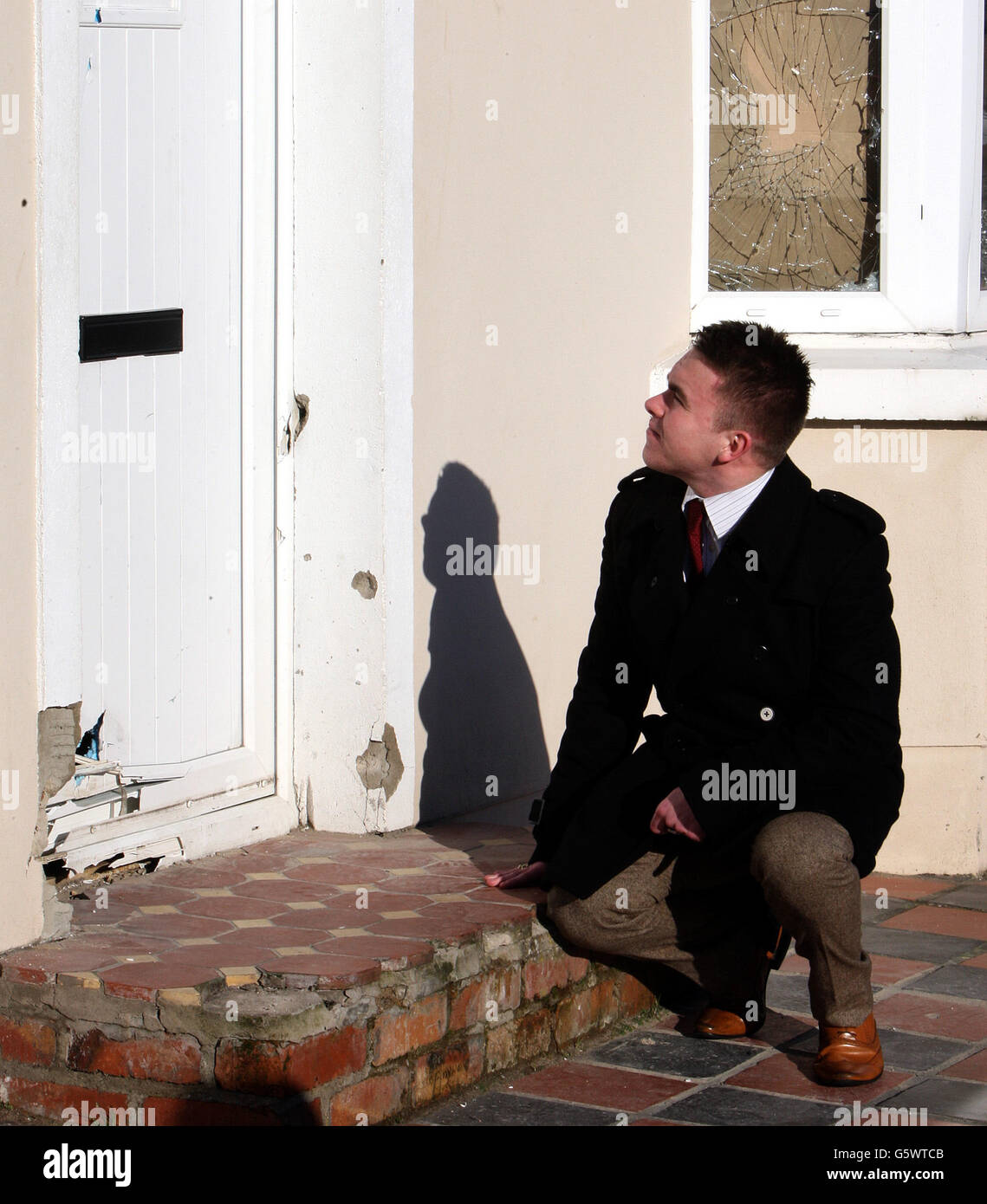 Guy Spence, conseiller du DUP, enquête sur les dommages causés à l'avant d'une maison dans le nord de Belfast, après qu'une bombe ait explosé à la porte d'entrée dimanche soir, blessant une femme et deux chiens. Banque D'Images