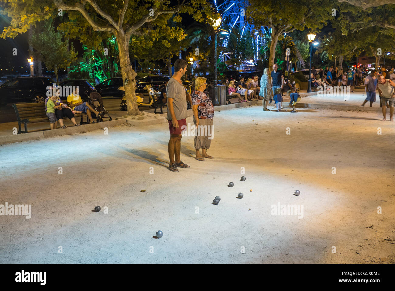 Un groupe de personnes qui jouent le jeu du ballon (la pétanque) en soirée d'été dans Le Lavandou, Var, Provence-Alpes-Côte d'Azur, France Banque D'Images