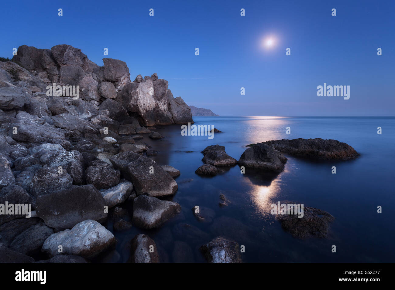 Paysage de nuit avec la pleine lune, chemin des roches lunaires et en été. Paysage de montagne à la mer Banque D'Images