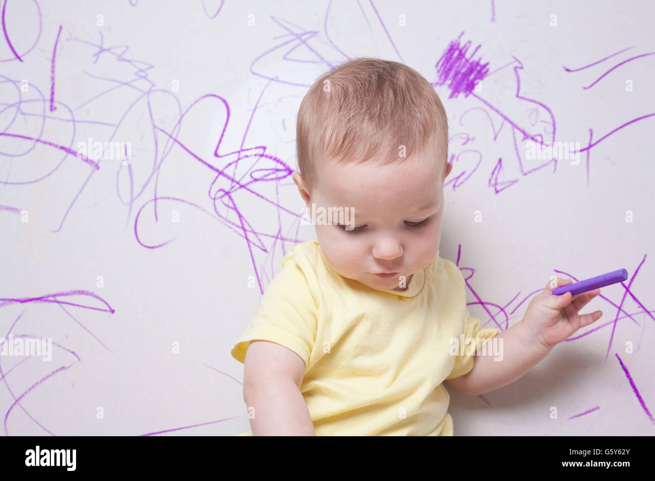 Baby Boy dessin avec crayon de cire sur le mur de plâtre Banque D'Images