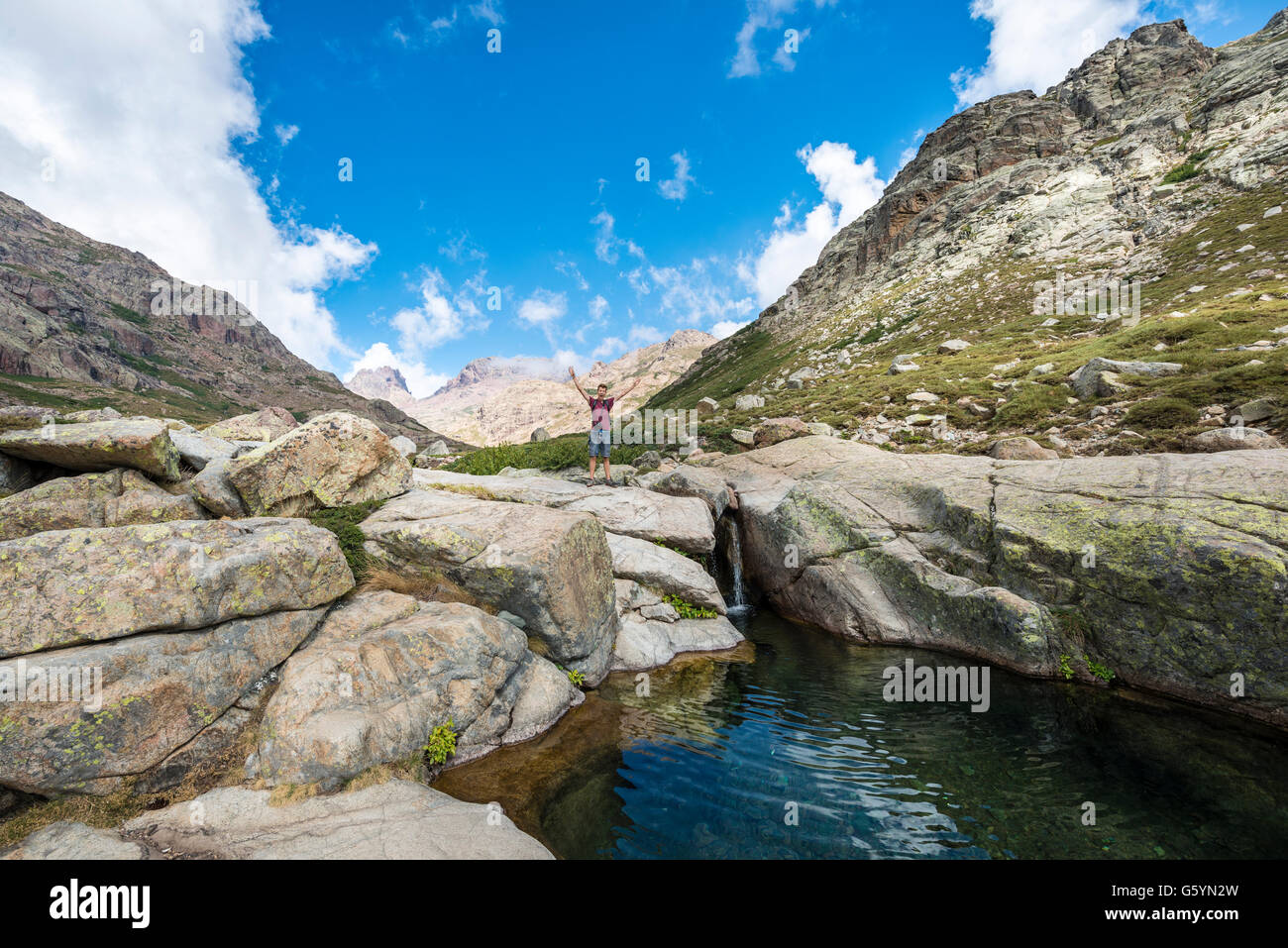 Jeune homme debout à côté d'une petite cascade avec piscine dans les montagnes, rivière Golo, Parc Naturel de la Corse Banque D'Images