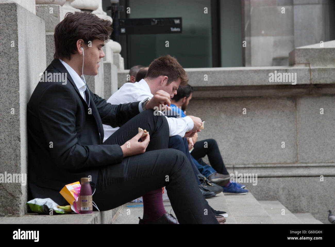 Pause déjeuner d'été dans le centre-ville de Londres s'asseoir sur les marches de travailleurs Royal Exchange de manger le déjeuner Banque D'Images