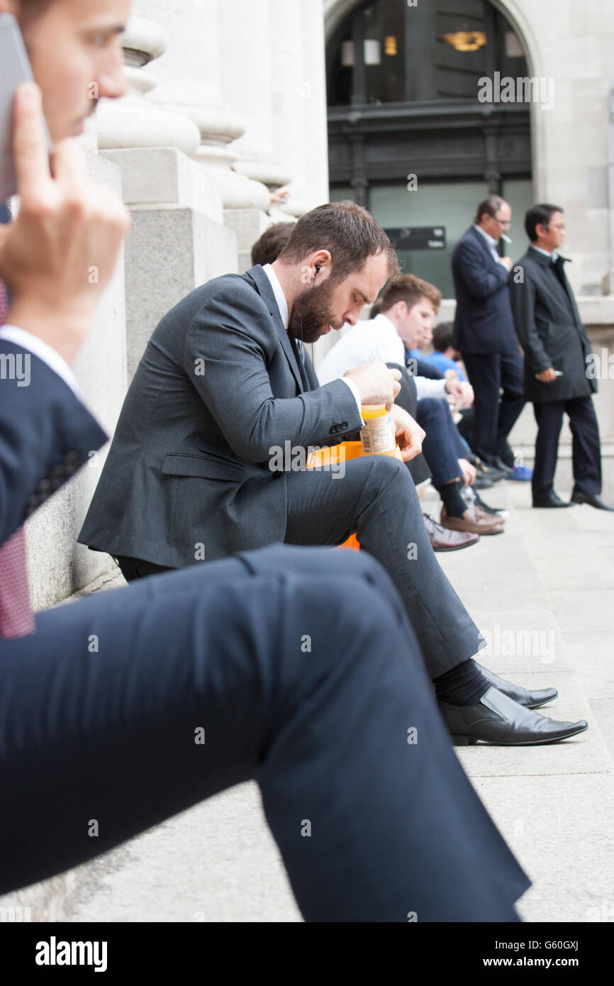 Pause déjeuner d'été dans le centre-ville de Londres s'asseoir sur les marches de travailleurs Royal Exchange de manger le déjeuner Banque D'Images